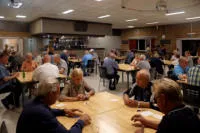 Mensen aan tafels in zaal Kempengalm